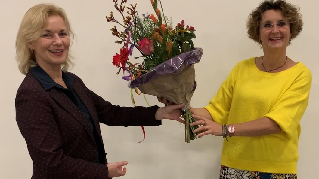 Bestuursvoorzitter Cora Coster reikt ter felicitatie een bos bloemen uit aan Alma Feenstra