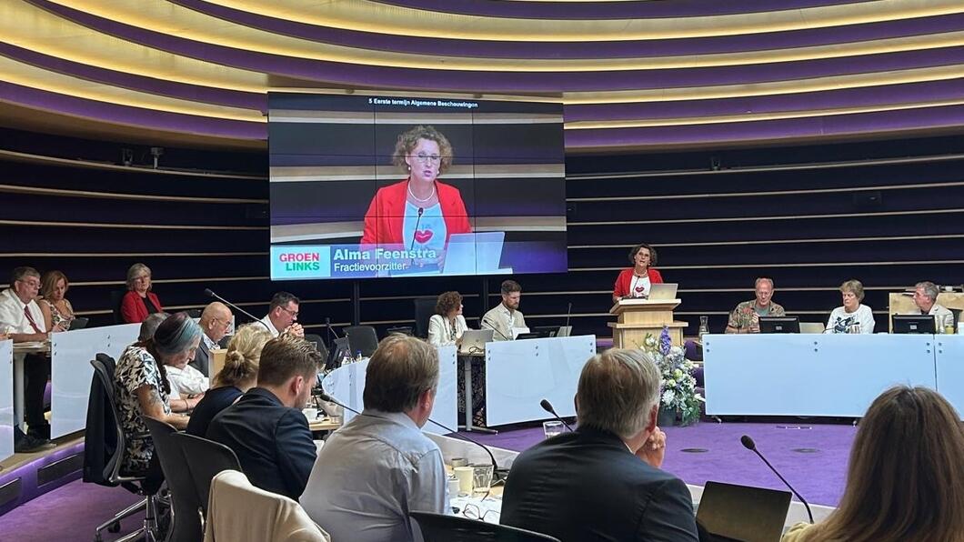 De raadzaal met raadsleden luistert naar Alma Feenstra die achter het spreekgestoelte staat en hen toespreekt