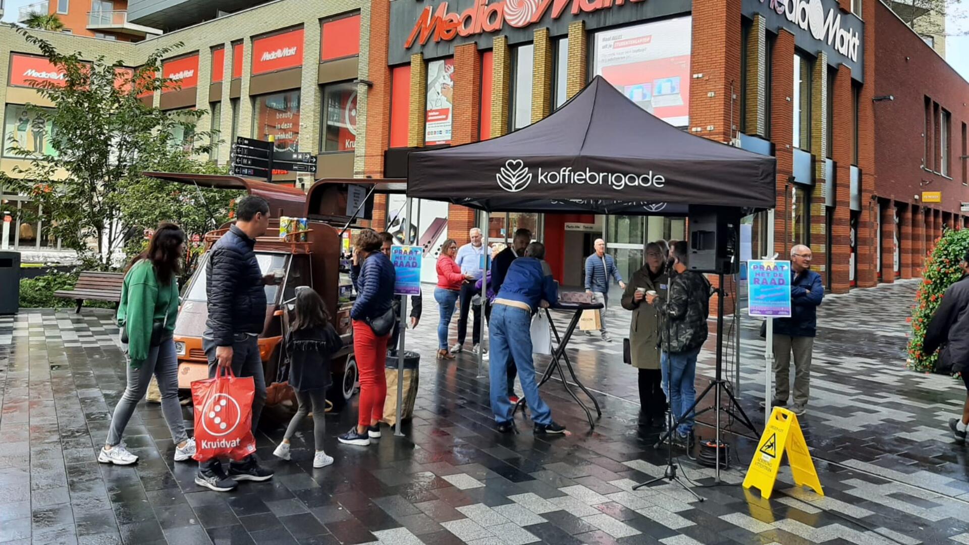 raadsleden en inwoners zijn met elkaar in gesprek bij een koffiekar voor het stadshuis