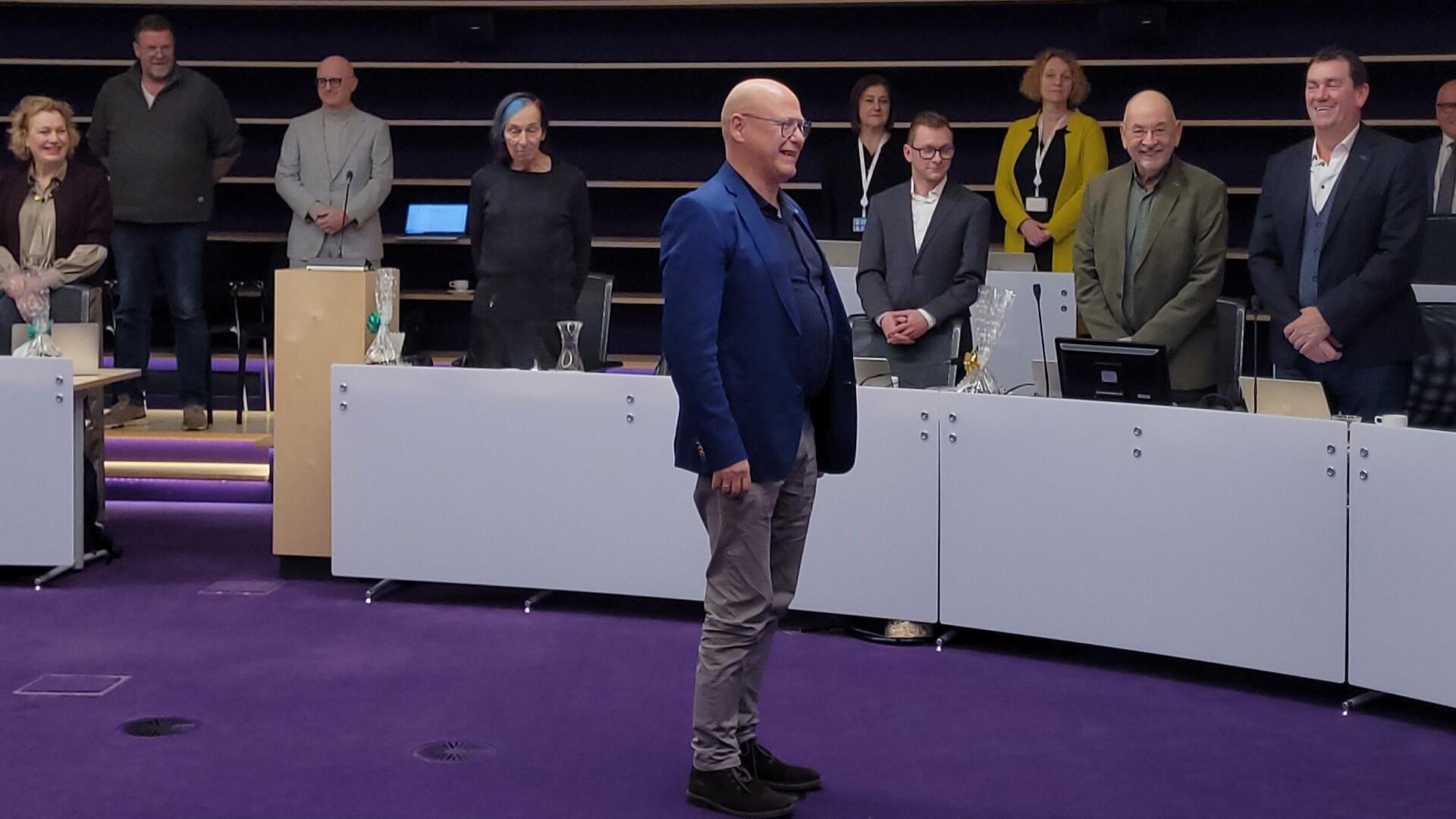 Steunfractielid Dirk de Knecht staat in de raadszaal van Nieuwegein, achter hem staan raadsleden terwijl Dirk de belofte aflegt